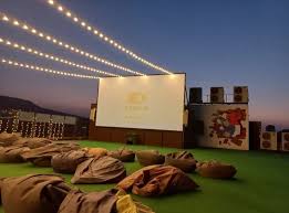 Magical outdoor cinema under starlit sky with comfortable seating and large screen surrounded by nature